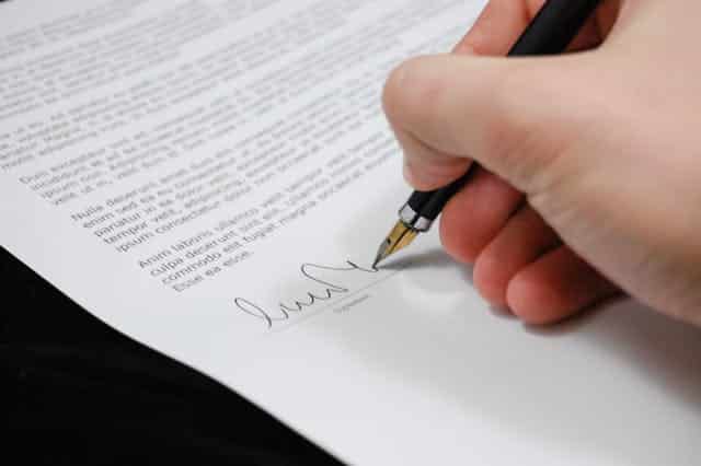 Hand signing a legal document with a pen.